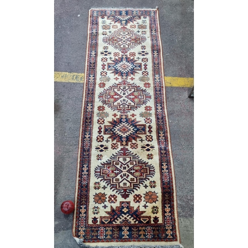 389 - Star Lot : A beautiful hand knotted wool Kazak runner rug. In classic shades of red, blue and cream.... 