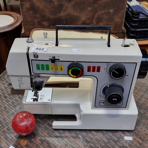 402 - An Empisal Cresta sewing machine model 999 A. Comes with cover and manuals.