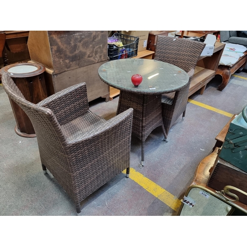 403 - A good quality 3 piece garden rattan furniture set comprising of a round table with glass top and a ... 