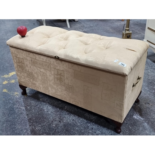 704 - An elegant ottoman bench with bottom back detailing and cabriole feet. Upholstered in a cream fabric... 