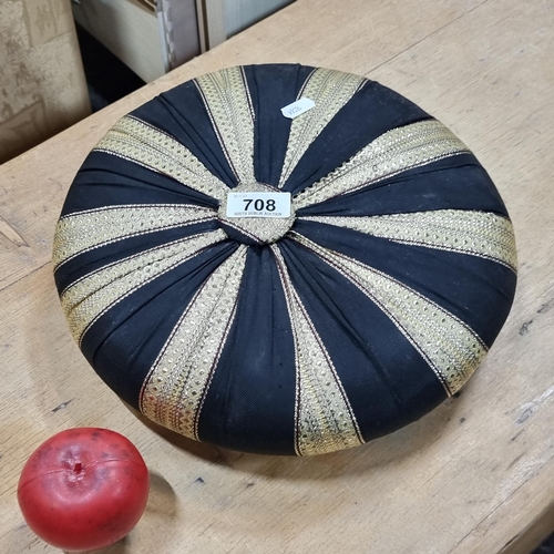 708 - A well made stool with three turned legs accompanied by an ornate gold and black seat cushion.