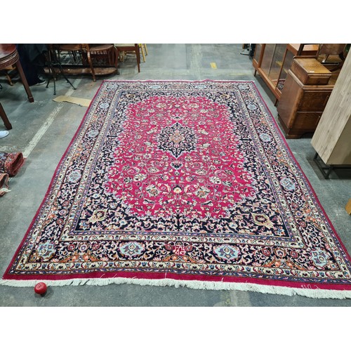 730 - A beautiful and very large hand knotted wool rug with a floral design in jewel tones of red and navy... 