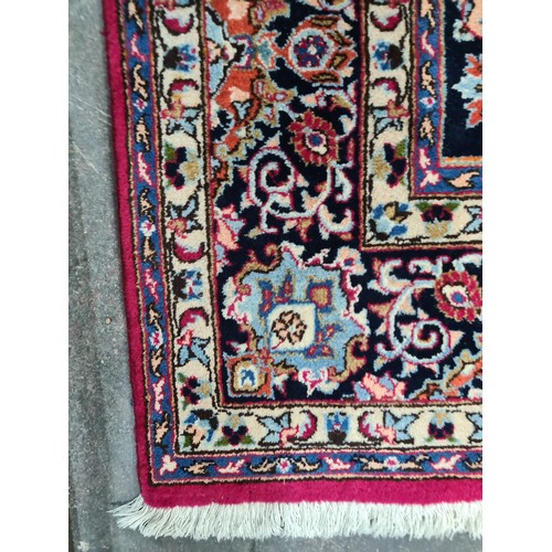 730 - A beautiful and very large hand knotted wool rug with a floral design in jewel tones of red and navy... 