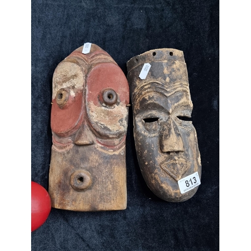 813 - Two vintage African wooden masks, one hand painted example with large eyes, the other with more almo... 