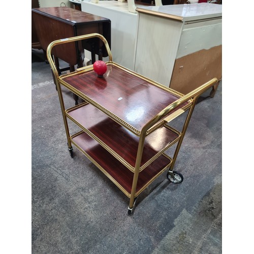 954 - An attractive drinks trolley with three tiers, pierced brass surrounds and castors.