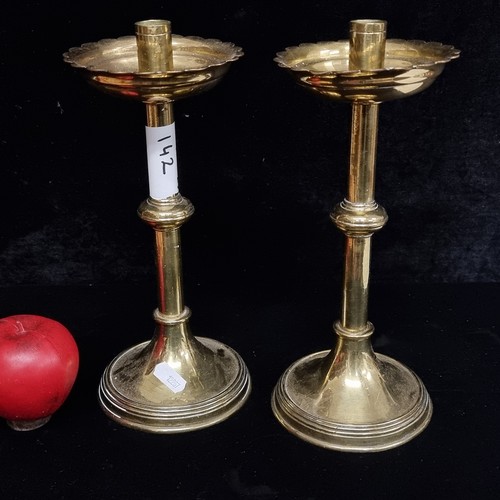 142 - A pair of vintage ecclesiastical brass candle holders with scalloped drip trays.