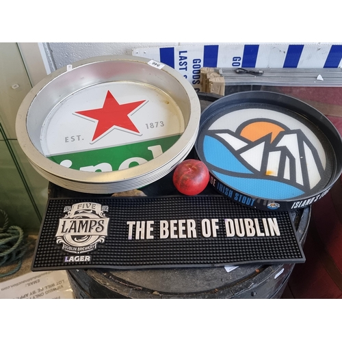 946 - A collection of ten pub items including Heineken branded trays and a rubber Five Lamps beer mat.