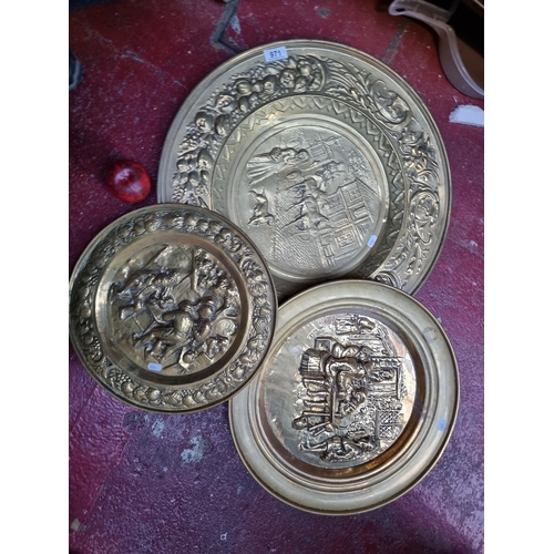 971 - A set of three graduated brass decorative plates featuring lovely hammered / repousse design. Two fe... 