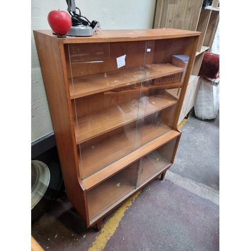 986 - Star Lot : A fashionable mid century teak bookcase with sliding glass doors. Good storage in this pi... 