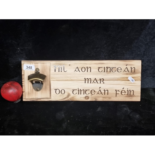 348 - A charming wooden plaque with an integrated bottle opener, featuring Irish inscription. Expertly mad... 