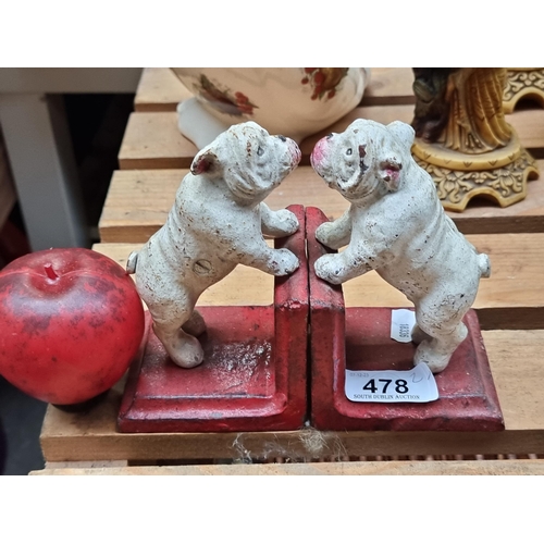 478 - Quaint vintage cast iron doorstops, delightful twin bulldogs poised in play, set on a classic red ba... 