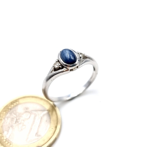 961 - A 9K white gold ring set with a cabochon blue stone with white spinel shoulders, ring size O, weight... 