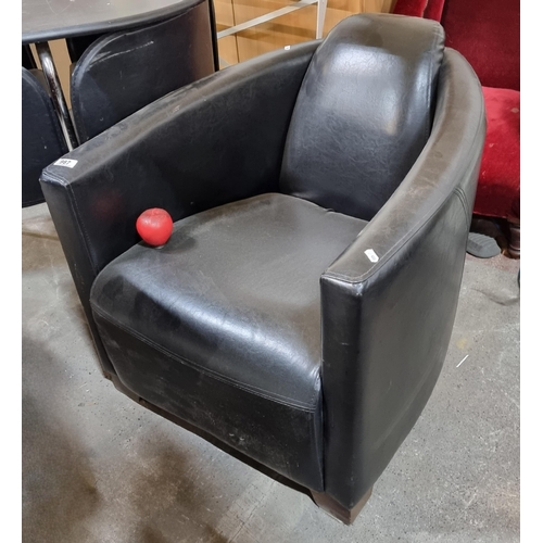 987 - A stylish art deco style armchair with padded backrests and curved arm rests. In a black leather fin... 