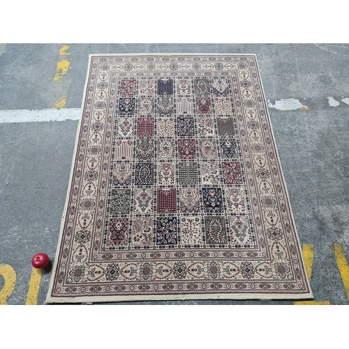 945 - A fabulous woolen rug featuring an intricate foliate and geometric pattern in shades of beige, red a... 