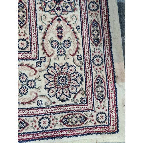 945 - A fabulous woolen rug featuring an intricate foliate and geometric pattern in shades of beige, red a... 