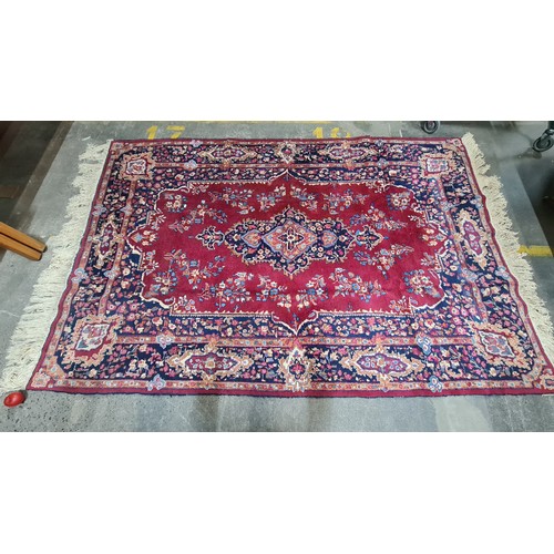 973 - Star Lot : A beautiful large hand knotted woolen rug with a floral design. In shades of ruby red, na... 