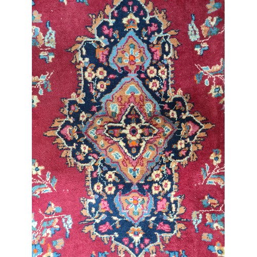 973 - Star Lot : A beautiful large hand knotted woolen rug with a floral design. In shades of ruby red, na... 