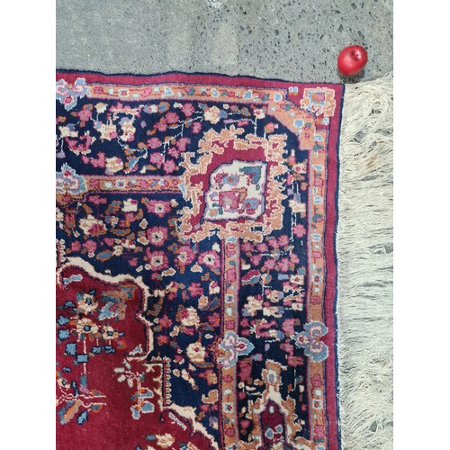 973 - Star Lot : A beautiful large hand knotted woolen rug with a floral design. In shades of ruby red, na... 