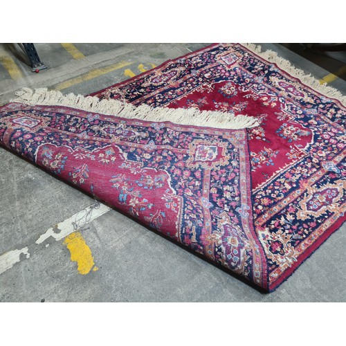 973 - Star Lot : A beautiful large hand knotted woolen rug with a floral design. In shades of ruby red, na... 