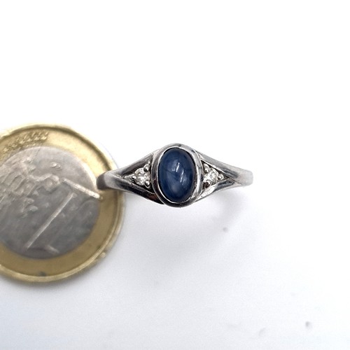 961 - A 9K white gold ring set with a cabochon blue stone with white spinel shoulders, ring size O, weight... 