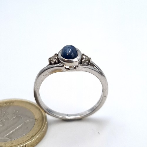 961 - A 9K white gold ring set with a cabochon blue stone with white spinel shoulders, ring size O, weight... 