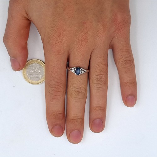 961 - A 9K white gold ring set with a cabochon blue stone with white spinel shoulders, ring size O, weight... 