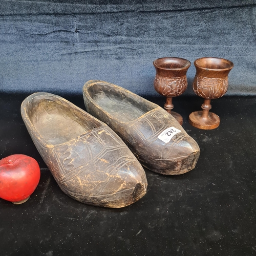 242 - Four interesting hand carved wooden items including a pair of vintage clogs boasting a foliate motif... 