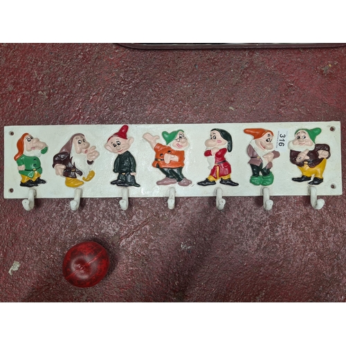 316 - A cast metal coat rack, whimsically adorned with seven hand-painted dwarf figures, a charming piece.