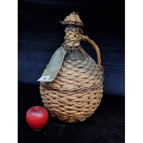 192 - A 1934 Woven Demijohn: This vintage demijohn features robust craftsmanship with its intricately wove... 