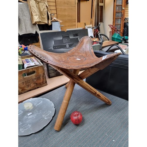 469 - A vintage tripod stool with a tooled leather seat.