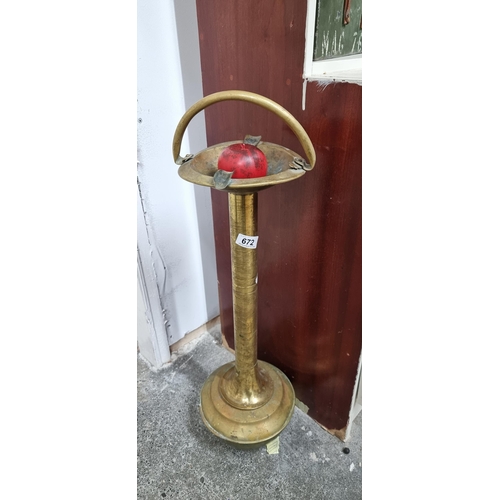 An elegant antique brass floor standing ashtray with handle and a weighted base.