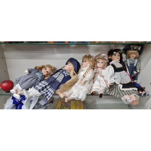 730 - A collection of 6 charming porcelain dolls with blue glass eyes, eyelashes and long hair. All wearin... 