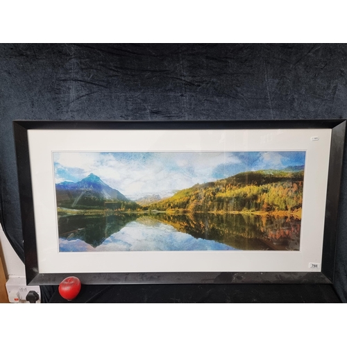 766 - A large print of a watercolour painting showing a panoramic scene of a lake surrounded by forest and... 