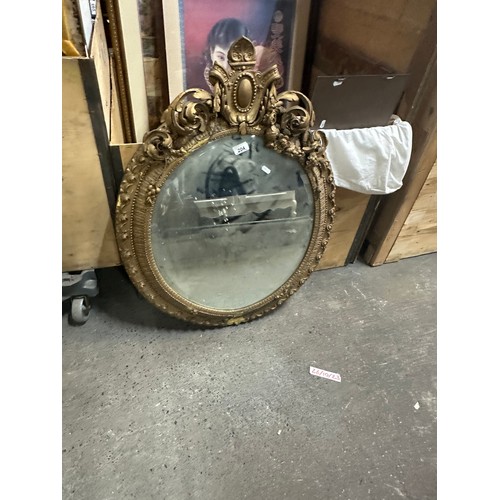 952 - Star Lot - An elegant antique Regency  wall mirror. A large oval form example with an ornamental ped... 