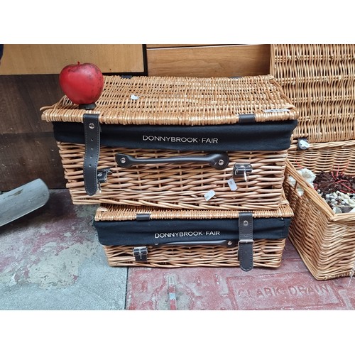 415 - Two charming Donnybrook Fair wicker picnic hampers with leather straps and branded liners. In slight... 