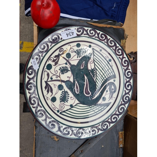 434 - A large studio pottery ceramic plate featuring a dynamic fish design amid stylized vegetal motifs. I... 