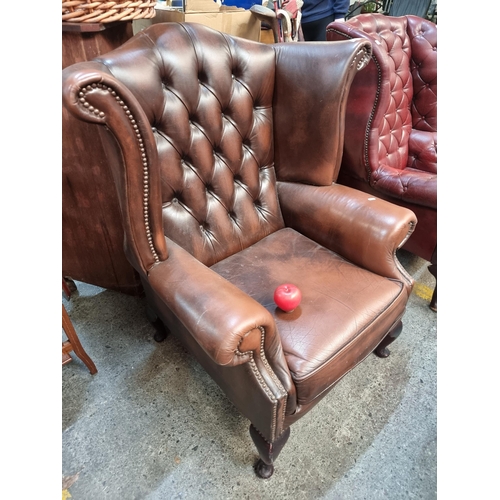 570 - Star Lot : A handsome Chesterfield style wingback armchair in a timeless brown finish. Featuring but... 