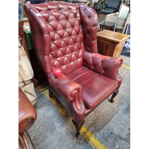 571 - Star Lot : A striking Chesterfield style wingback armchair in an attractive red finish. Boasting but... 