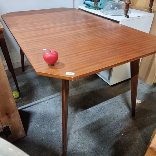 653 - A stylish mid century modern dining table with angular cut corners, held on splayed tapered legs. In... 