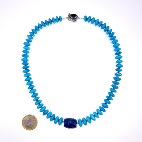 550 - An interesting necklace of graduated disc turquoise stones set with a lapis lazuli accent with black... 