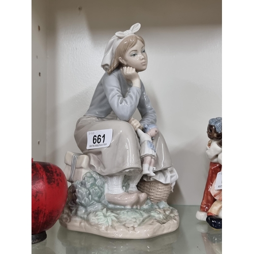 661 - A beautiful large  Lladro figure of a sitting young girl clutching her doll.