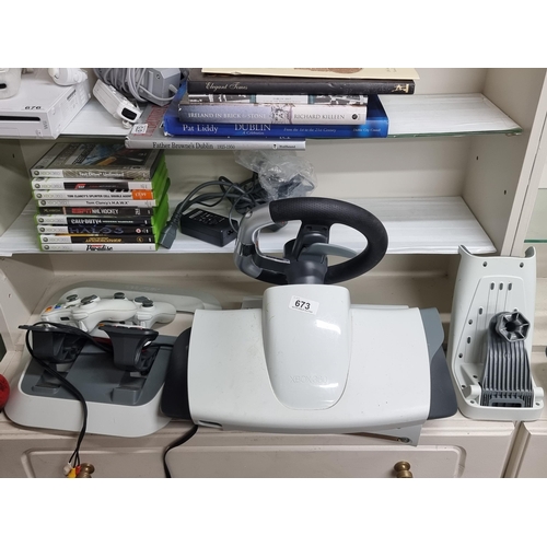 673 - An Xbox 360 console along with a selection of games, two controllers and driving accessories etc.