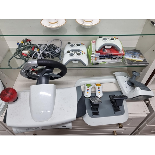 680 - An Xbox 360 console along with a selection of games, two controllers and driving accessories.