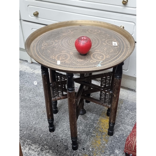 683 - A striking vintage Moroccan coffee table with a heavy brass tray top boasting a rich figural and zoo... 