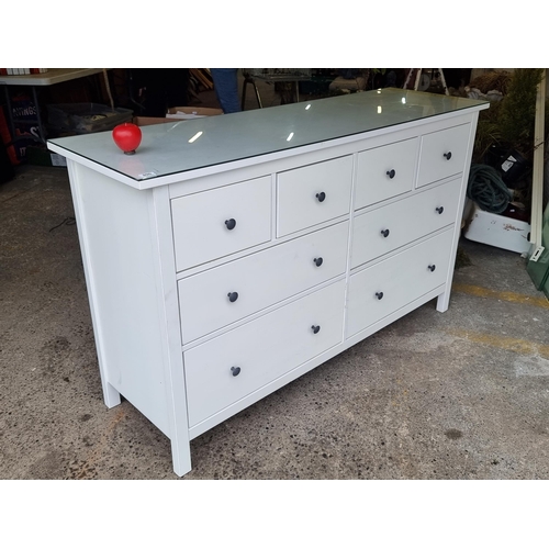 800 - Star Lot : A sleek dresser with 7 drawers. In a white finish with black metal handles and a glass pr... 