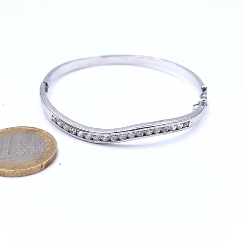 907 - An exquisite sterling silver (stamped 925) bangle boasting a curved 18 gem setting. Fitted with an o... 