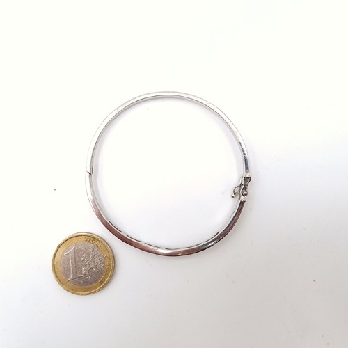 907 - An exquisite sterling silver (stamped 925) bangle boasting a curved 18 gem setting. Fitted with an o... 