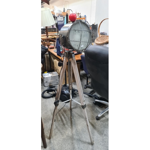 1032 - A nautical style floor lamp with a large light in a metal cage and a wooden tripod with adjustable h... 