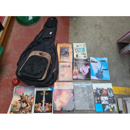 307 - A guitar case holding a number of music books including titles such as 