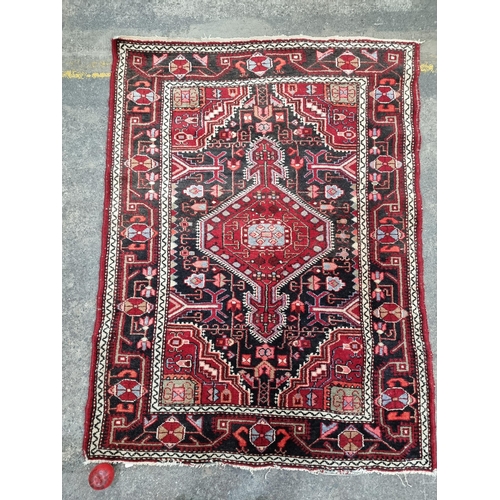 347 - Star lot : A charming hand knotted woollen rug with a geometric pattern in shades of red, black and ... 